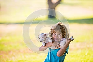 Cute child boy feels delighted, carries little puppy dog, expresses tender emotions, care and love to small doggy