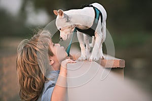 Cute child boy kiss puppy, feels delighted, pleasure, carries little baby dog, expresses tender emotions, care and love