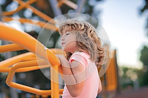 Cute child boy plays on playground. Kid climbing on playground.