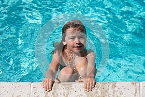 Cute child boy swim in swimming pool, summer water background with copy space. Funny kids face. Kids summer vacation