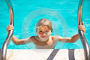 Cute child boy swim in swimming pool, summer water background with copy space. Funny kids face. Summer activities for