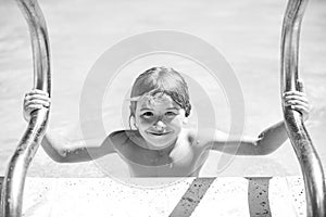 Cute child boy swim in swimming pool, summer water background with copy space. Funny kids face. Summer activities for