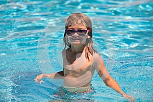 Cute child boy swim in swimming pool, summer water background with copy space. Funny kids face. Summertime and swimming