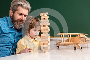 Cute child boy with teacher playing in classroom near blackboard desk. Private kids tutoring. Home school for pupil