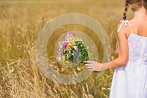 Cute child carrying bouquet on field