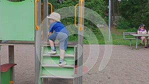 Cute child climbing on children slide in beautiful nature park.