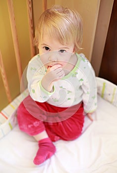 Cute child in crib sucking her finger