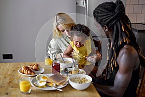 cute child is crying whilte taking breakfast with parents, naughty daughter