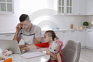 Cute child disturbing stressed man in kitchen. Working from home during quarantine