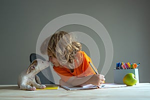 Cute child and dog playing at home. Back to school. A Cute little boy with pet puppy doing homework.