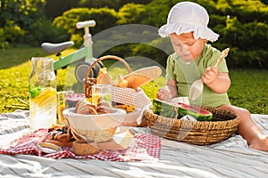 Cute child eating watermelon on picnic blanket in garden