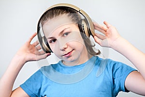 Cute child enjoying dance music, girl listening to music in headphones on grey background. Looking at camera