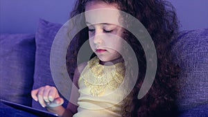 Cute child entertaining with tablet. Little girl spending leisure time playing mobile game in the and crushes the bright