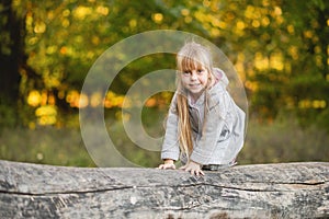 Cute child girl on all fours balances on a fallen log