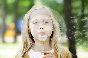 Cute child girl blowing dandelion