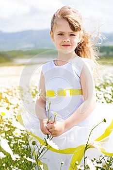 Cute child girl at camomile field