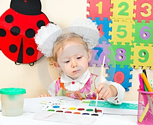 Cute child girl drawing with colorful pencils and felt-tip pen in preschool in kindergarten