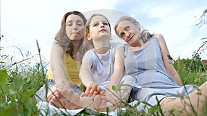 Cute child girl with her young mother and senior grandmother are having picnic during summer outdoor in nature, mothers