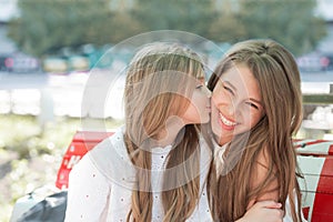 Cute child girl kissing her older teenager sister