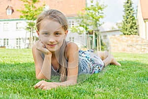 Cute child girl laying in grass in city park