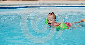 Cute child girl learning to swim in swimming pool on summer vacations