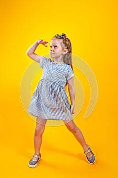 Cute child girl looking far away with hand over head on yellow background