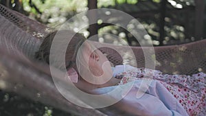 Cute child girl lying on hammock and relax at the garden.