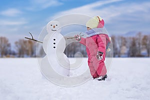 Cute child girl making snowman at bright snowy place. Winter outdoor activities photo