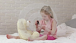 Cute child girl playing doctor with teddy bear