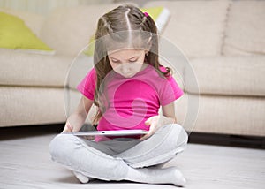Cute child girl playing with a tablet computer.