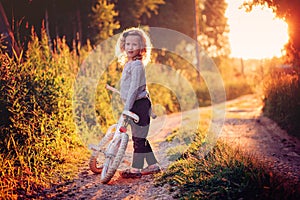 Cute child girl riding bicycle on summer sunset country road