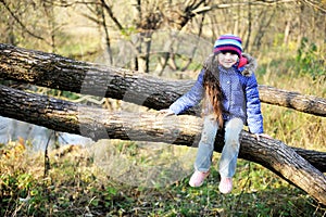 Cute child girl sitting on a tree branch