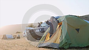 Cute child girl wakes up and comes out from tourist tent and stretches