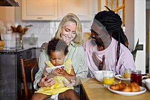 Cute child girl watching video cartoons on smartphone while having meal with parents