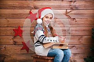 Cute child girl writing letter santa home near the Christmas tree