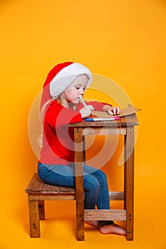 Cute child girl writing letter to Santa Claus on yellow background