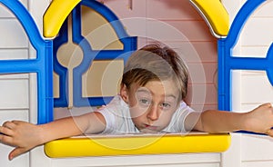 Cute child having a bored expression in toy house