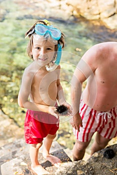 Cute child, holding sea urchin on the beach