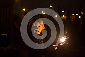 Cute child, holding sparkler at new year eve in garden