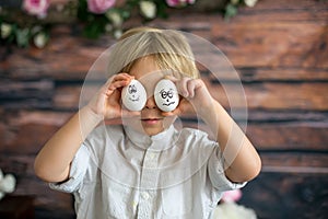 Cute child, holding white eggs with emotions drawn on them, funny faces