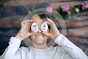 Cute child, holding white eggs with emotions drawn on them, funny faces