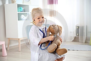 Cute child imagining herself as doctor while playing with stethoscope and toy bunny