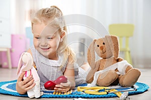 Cute child imagining herself as doctor while playing with toy bunny