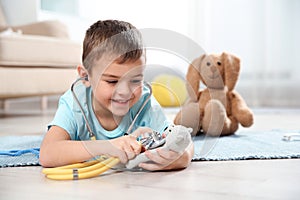 Cute child imagining himself as doctor while playing with stethoscope and toy