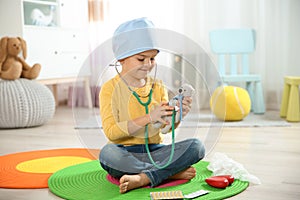 Cute child imagining himself as doctor while playing with stethoscope and toy bear