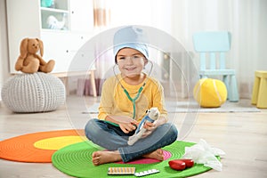 Cute child imagining himself as doctor while playing with stethoscope and toy bear