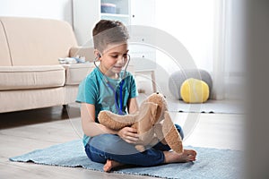 Cute child imagining himself as doctor while playing with stethoscope and toy bunny