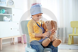 Cute child imagining himself as doctor while playing with stethoscope and toy bunny