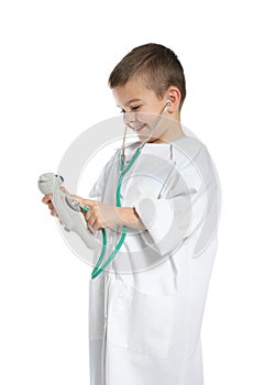 Cute child imagining himself as doctor while playing with stethoscope and toy on white