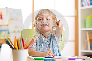 Cute child little boy drawing with felt-tip pen in kindergarten classroom